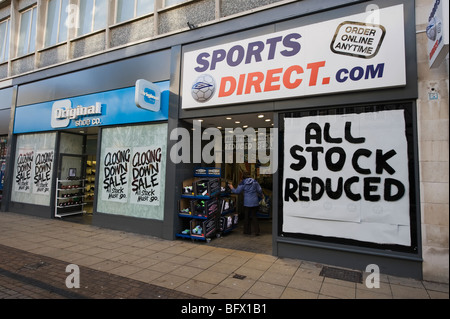 Two shop fronts displaying large signs which state that their stock is reduced in price. Stock Photo