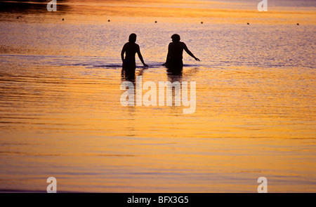 A couple wades during sunset at Lake Megunticook Camden Maine Stock Photo