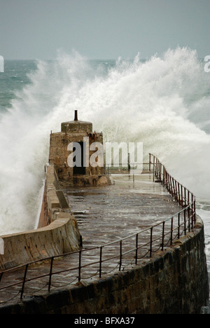 waves crashing against the old pier at portreath in cornwall, uk Stock Photo