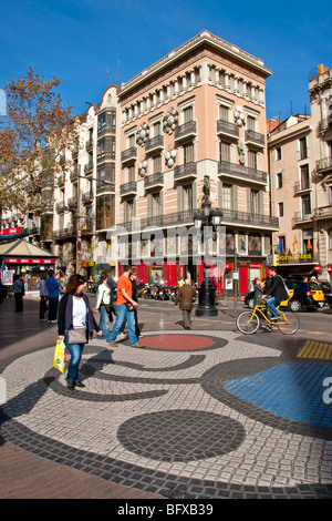 Las Ramblas in Barcelona with pedestrians on Joan Miro mosaic tile design in front of art deco building formerly an umbrella sh Stock Photo