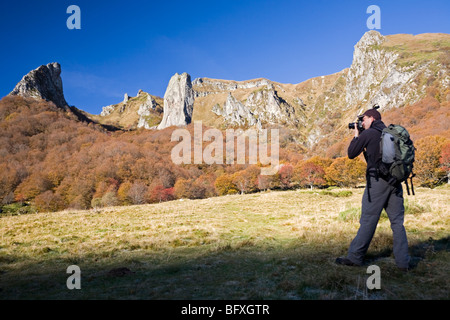 A hiker photographing the Chaudefour valley, in Autumn (France). Randonneur photographiant la vallée de Chaudefour, en automne. Stock Photo
