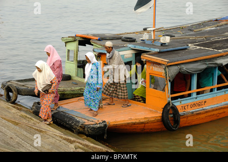 Malay or Malaysian Muslim Women in Islamic Dress Leave a Ferry Boat on the Waterfront at Kuala Terengganu, Malaysia Stock Photo