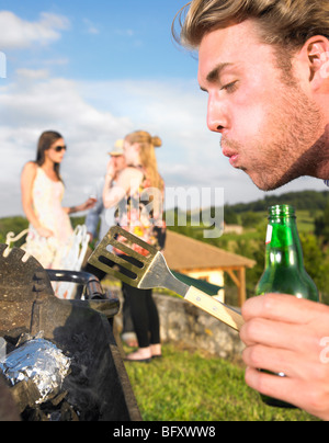 young man tending barbecue Stock Photo