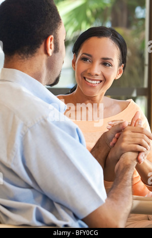 A happy African American man and woman couple sitting down and holding hands. Stock Photo