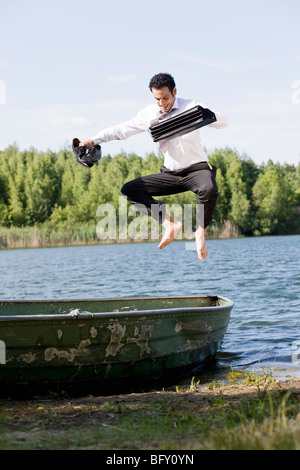 businessman jumping on rowboat Stock Photo