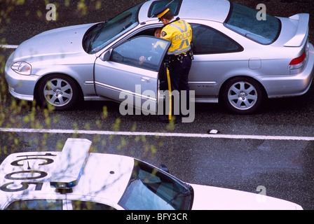 Police Officer writing a Ticket for Traffic Violation Incident to Motorist driving in a Car Stock Photo