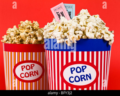 Two popcorn buckets over a red background. Movie stubs sitting over the popcorn. Stock Photo