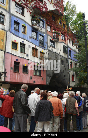 A group of tourists in front of the colourful facade to Hundertwasser House, Vienna, Austria Stock Photo