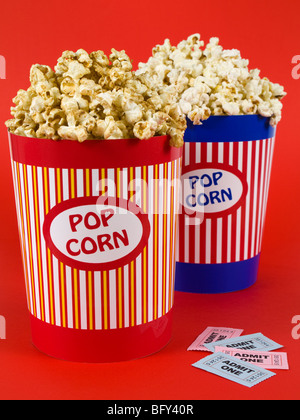 Two popcorn buckets over a red background. Movie stubs sitting aside. Stock Photo