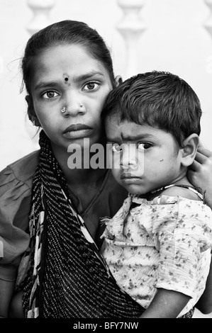 Poor Indian girl cradling her baby sister in a sling. black and white Stock Photo