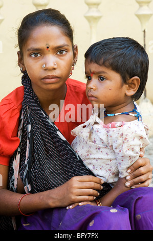 Poor Indian girl cradling her baby sister in a sling. black and white ...