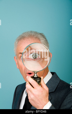 Businessman holding magnifying glass over eye Stock Photo