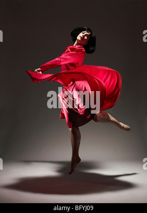 Woman in Red dress dancing under light Stock Photo