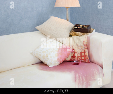 sofa with spilt red wine and chocolates Stock Photo