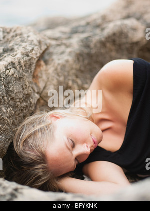 woman lying on rocks at cliffs Stock Photo