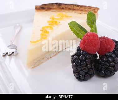 Lemon and Lime tart, with lemon peel on top, with raspberries, blackberries and mint in the foreground. Stock Photo