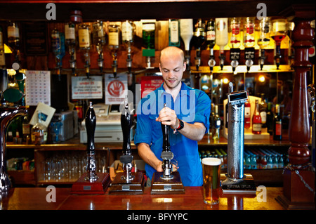 Barman standing behind bar in pub Stock Photo
