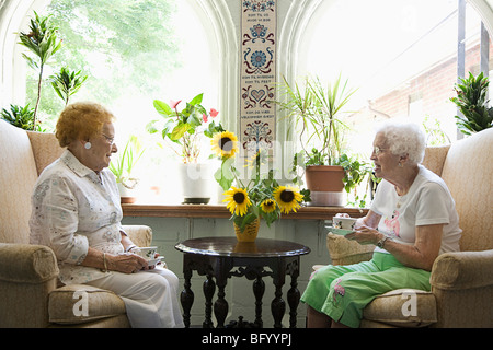 Two mature ladies having tea together and laughing Stock Photo - Alamy