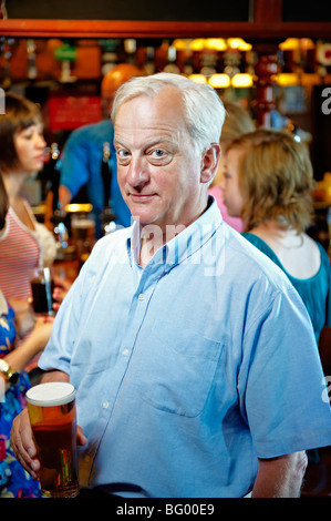 Older man holding glass of beer Stock Photo