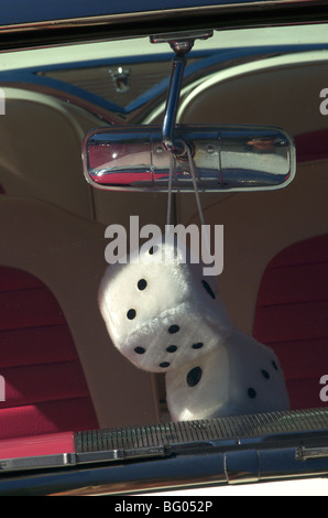 Fuzzy Dice hanging from rear view mirror of classic car Stock Photo