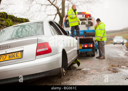 Removing a car that had its wheels stolen after being abandoned in the floods on kirkstone pass above Ambleside, Lake district, Stock Photo