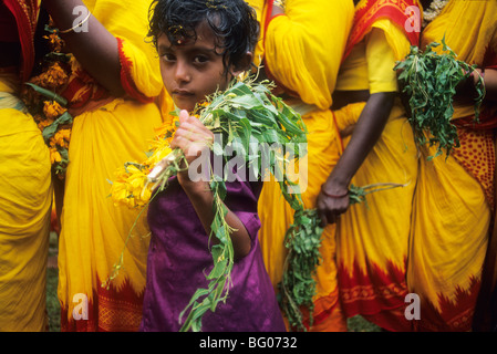 A young girl waits in line with her mother and other South India women to participate in a fire walking festival in the state of Tamil Nadu. Fire walking is an important ritual practiced by certain sections of Hindu society. The ritual is practiced by many Hindus in south India. The ritual is primarily dedicated to Amman an important femaled deity associated with the Shakti cult in South Indian and Tamil culture. The fire walking ritual is an act of self-purification. Stock Photo