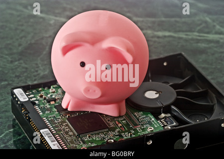 Piggy bank on top of a circuit board on a hard drive Stock Photo