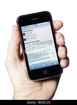 Male hand holding an old iPhone showing Twitter.com social media public timeline in 2009 Stock Photo