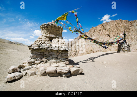 Stupas and Buddhist prayer flag mark the high pass on a mountain trekking route in Ladakh, Indian Himalayas. Stock Photo