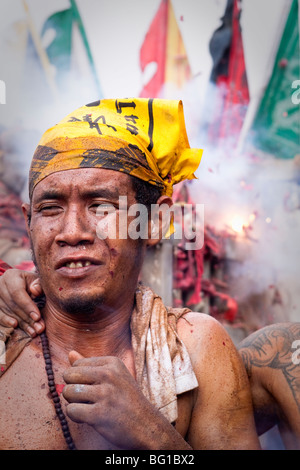 A fire cracker goes off during a procession at the vegetarian festival in Phuket, Thailand Stock Photo