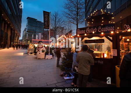 UK, England, Manchester, Spinningfields at night, visitors at outdoor German hot sausage snack stall Stock Photo