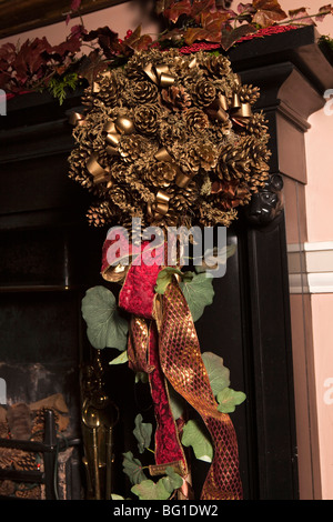 UK, England, Cheshire, Knutsford, Tatton Hall, entrance Hall, gilded Christmas pine cone decoration Stock Photo