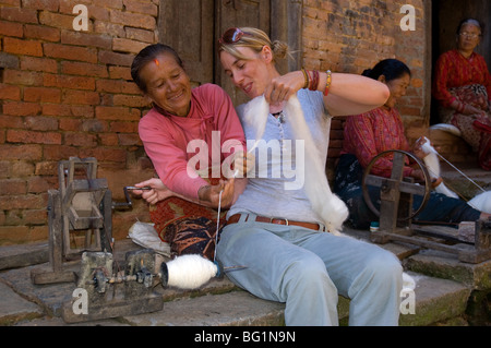 A western tourist learns to spin wool in the square at the small village of Bungamati, Nepal Stock Photo
