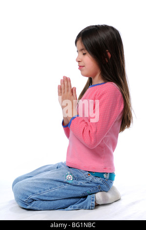 Little girl praying on her knees over a white background Stock Photo