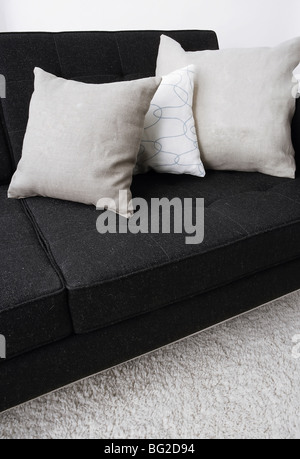 indoor setting, gray pillows laying on a black sofa Stock Photo