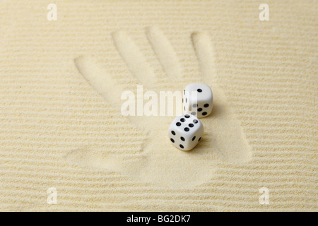 Print of a palm on sand with dices Stock Photo