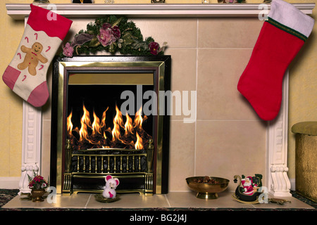 Christmas stockings hang over a Fireplace with a roaring fire in the grate Stock Photo