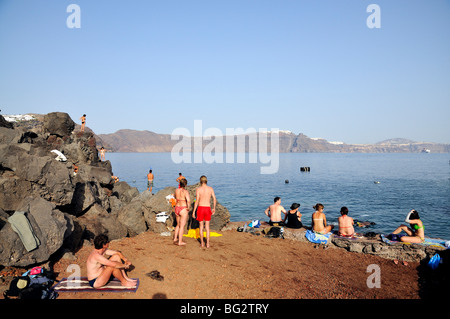 Tourists swimming and sunbathing at Ammoudi bay, near Oia village, Santorini island, Greece Stock Photo