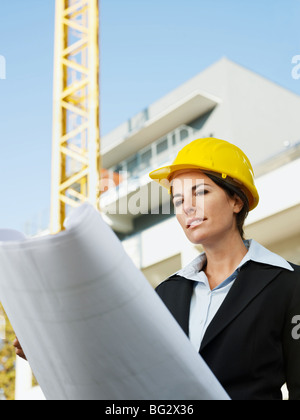 female engineer looking at blueprints in construction site Stock Photo