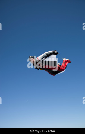 Skydiver within a special wingsuit is flying in the blue sky. The Birdman is going fast forward so the diver tracks a long time. Stock Photo