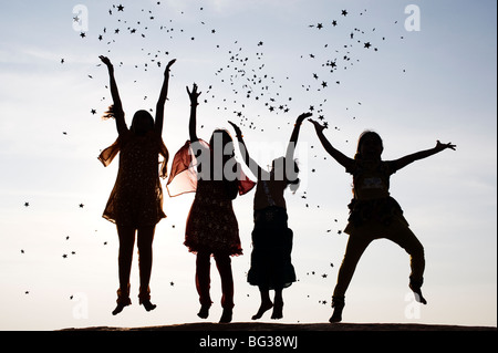 Silhouette of four young Indian girls jumping, throwing and catching stars. India Stock Photo
