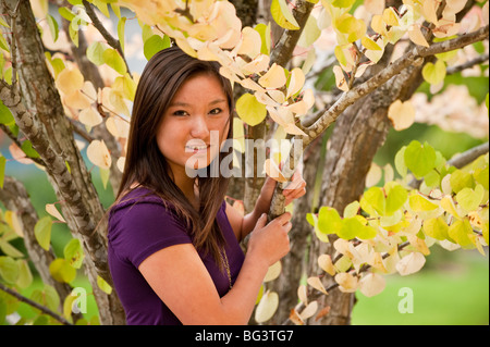 A teenage girl by a tree with golden foliage Stock Photo