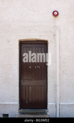 Closed door with red fire bell mounted above. Stock Photo