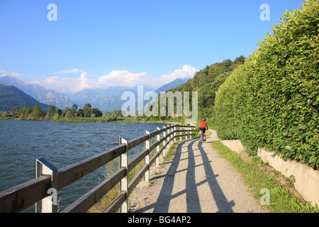 Man bikes along path at lake's edge, Lake Como, Italian Lakes, Lombardy, Italy, Europe Stock Photo