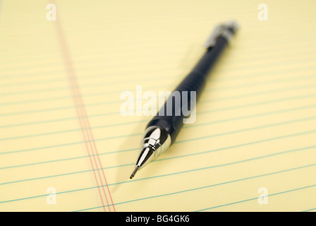 Blue mechanical pencil on a yellow legal pad. Focus on the tip of the pencil. Stock Photo