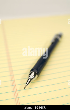 Blue mechanical pencil on a yellow legal pad. Focus on the tip of the pencil. Stock Photo