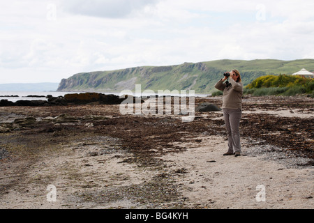 Person with binoculars on a beach at Kildonan The Isle of Arran, Scotland, June 2009 Stock Photo