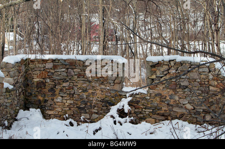 Ruins of an old stone barn covered in snow. Just the stone foundation is still standing. Stock Photo