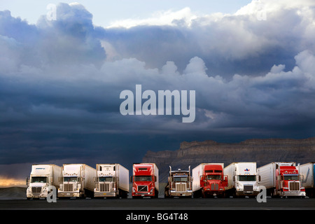Row of American trucks at  the Green River Utah truckstop with dark clouds of a rain and thunderstorm over the mountains. US USA Stock Photo