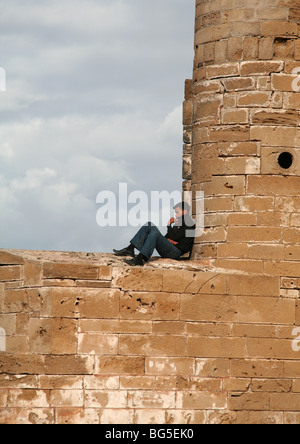 Man sitting on the Ramparts, walls Skala de la Ville, Essaouira, Moroc Stock Photo